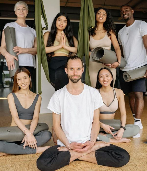 Diverse group of people smiling during a yoga class in a bright studio.