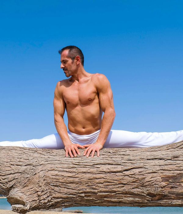 Man demonstrating strength and flexibility in a challenging yoga pose outdoors.